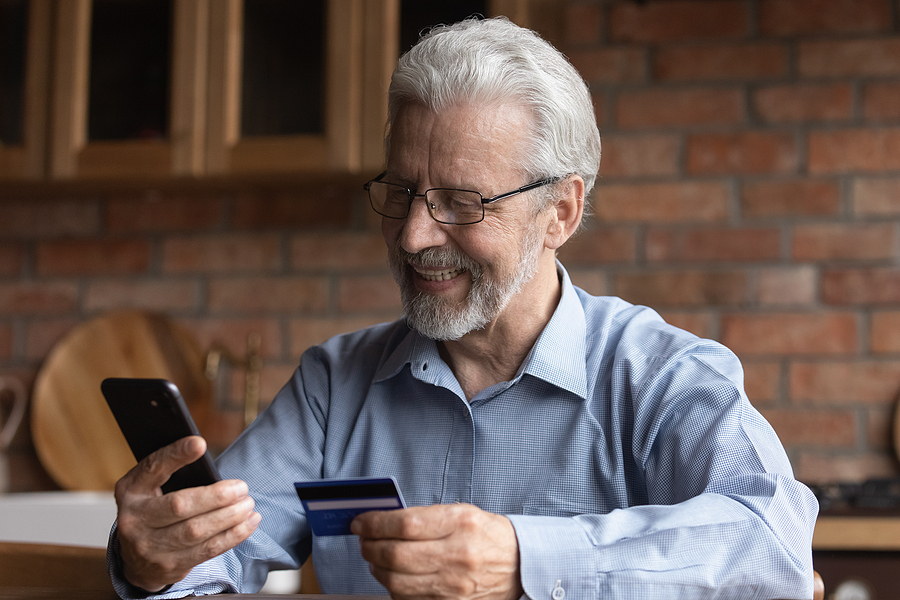 Smiling Old Man In Glasses Enjoying Shopping In Mobile App. gentleman making a payment